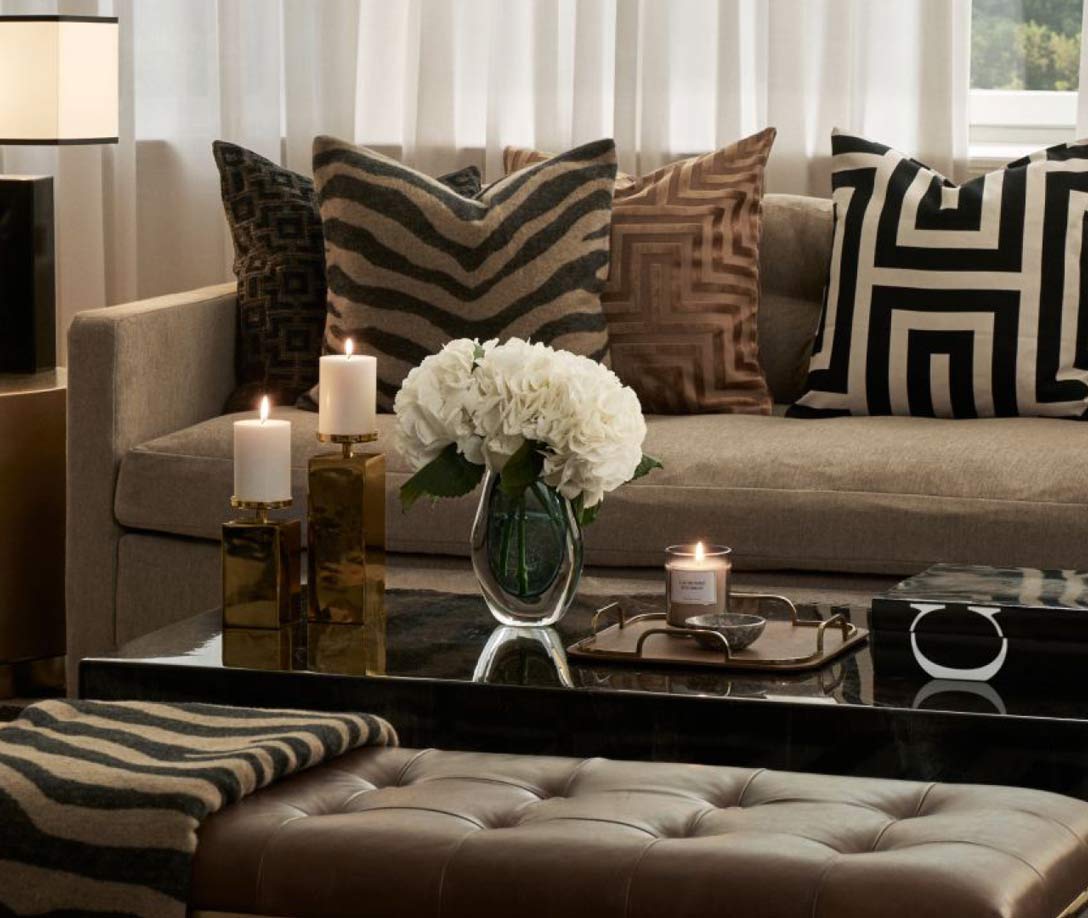 Sofa med pudder og sofabord med stearinlys og vaser